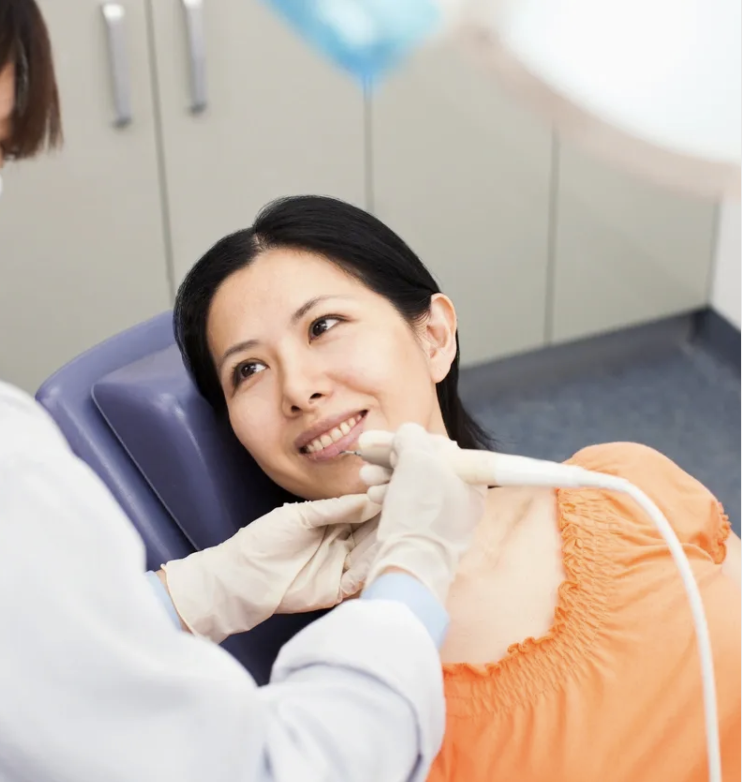 Woman in orange shirt in dentist's chair