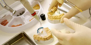 A hand works on dental molds.