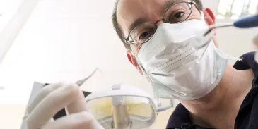 A male dentist holds a probe