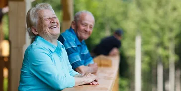 An older man at a balcony laughs,