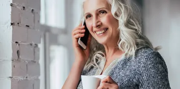 a woman with gray hair holding a phone.